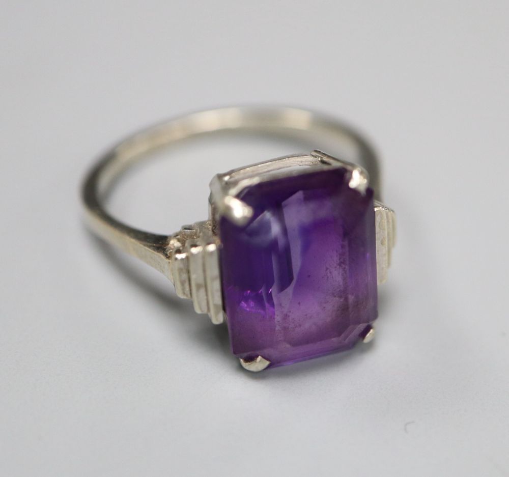 An Art Deco style 9ct white metal and emerald cut amethyst set dress ring, with stepped shoulders, size P, gross 3.8 grams.